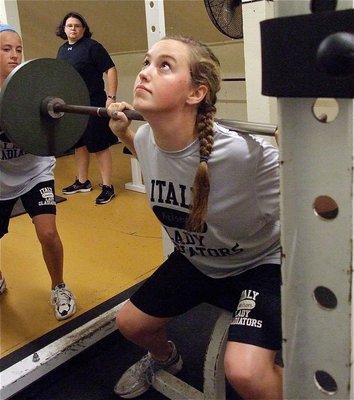 Image: Coach Lindsey Coffman judges while Britney Chambers helps to spot Kelsey Nelson during her lift.