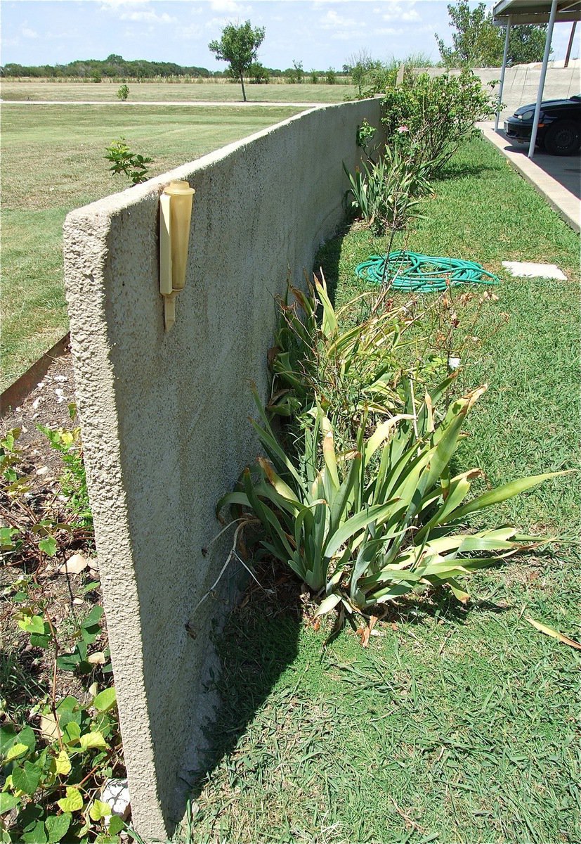 Image: This view demonstrates how thin the layer of concrete fence actually is yet still surrounds the property as if it were a massive wall.