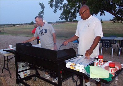 Image: Paul Cockerham and Coach Larry Mayberry serve up hamburgers and hot dogs for students and guests.