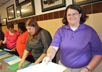 Image: Teacher/Coach Lindsey Coffman helps distribute paperwork to guests.