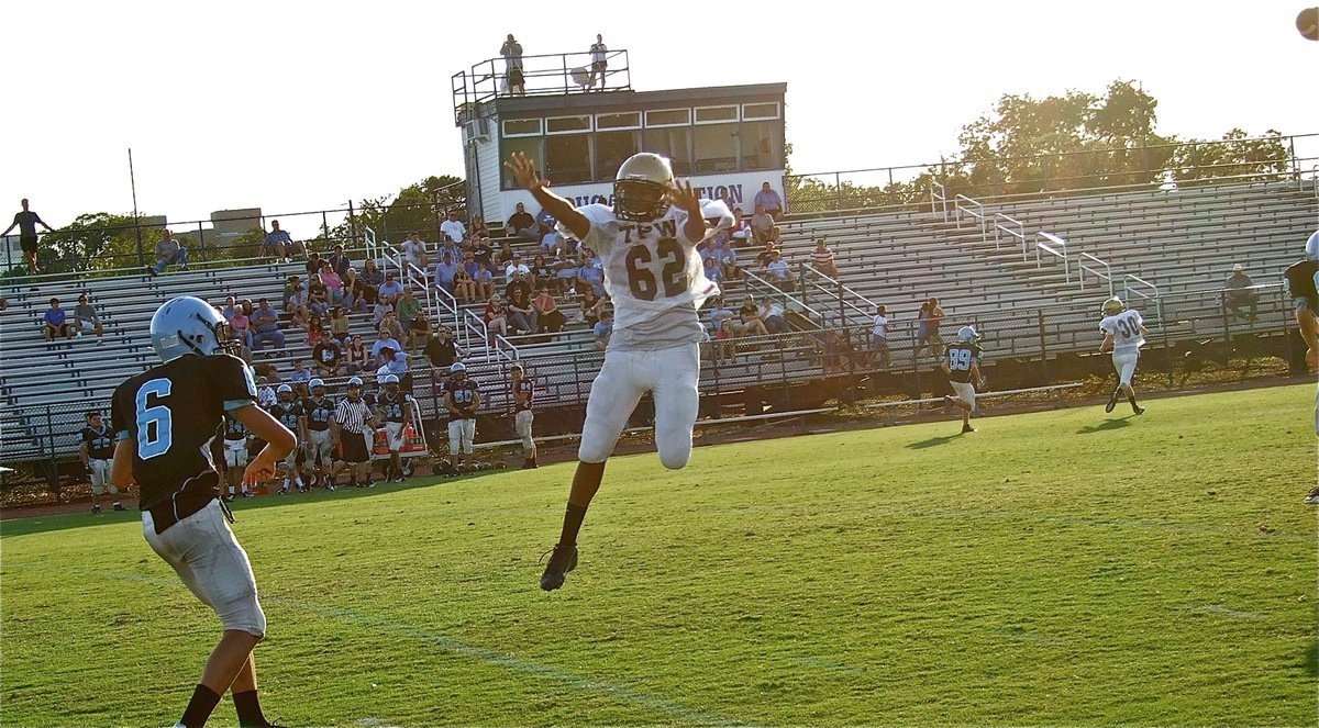 Image: “It’s not a plane, it’s Super Squirt!” Italy’s John “Squirt” Hughes(62) flies in to pressure the Cougar quarterback.