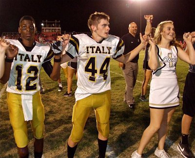 Image: Italy’s Eric Carson(12), Justin Wood(44) and Lady Gladiator cheerleader Kelsey Nelson lock pinkies during the school song. That’s IHS Principal Lee Joffrey in the background joining the celebration.