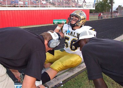 Image: No pain no gain! Zain Byers(50) receives a quick tape job from coach Nate Skelton and teammate Marvin Cox.