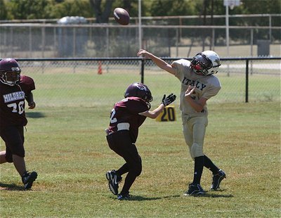 Image: IYAA A-Team quarterback Ryder Itson(2) gets the pass away just in time.