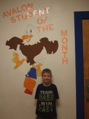 Image: Nathan once more in front to the “Student of the Month” wall.