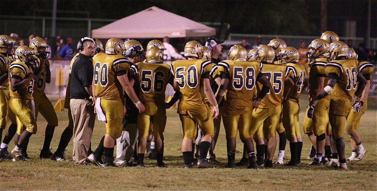 Image: Head coach Hank Hollywood convenes with his team in the fourth-quarter.