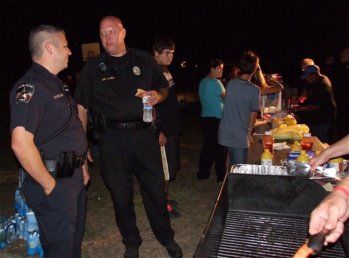 Image: Reserve Officer Pedro Gonzalez and Chief Hill enjoy a buffet of hot dogs during the Italy Police Department’s hosting of National Night Out.