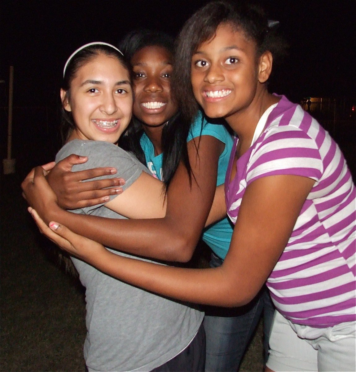 Image: Lizzie Garcia, Janae Robertson and Oleshia Anderson group hug against crime.