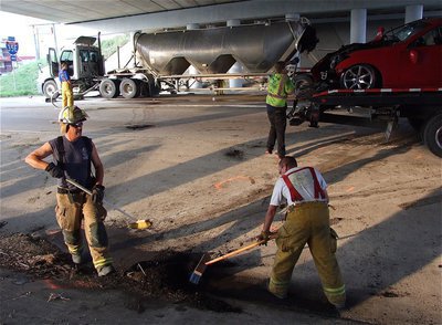 Image: Firefighters Bobby McBride and Brad Chambers clear the aftermath with help from Wesley Helms of Helms Garage.