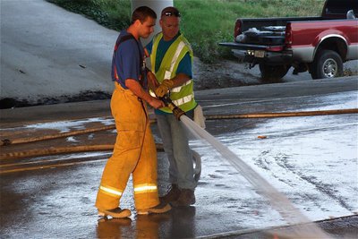 Image: Firefighters spray the diesel fuel from the roadway.