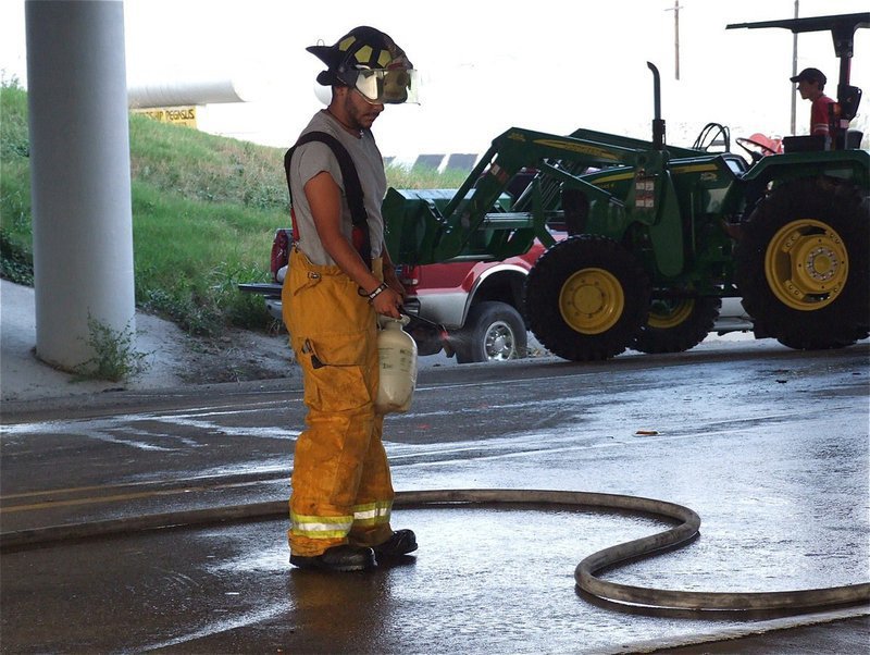 Image: IFD’s Michael Martinez sprays soap over the diesel fuel.