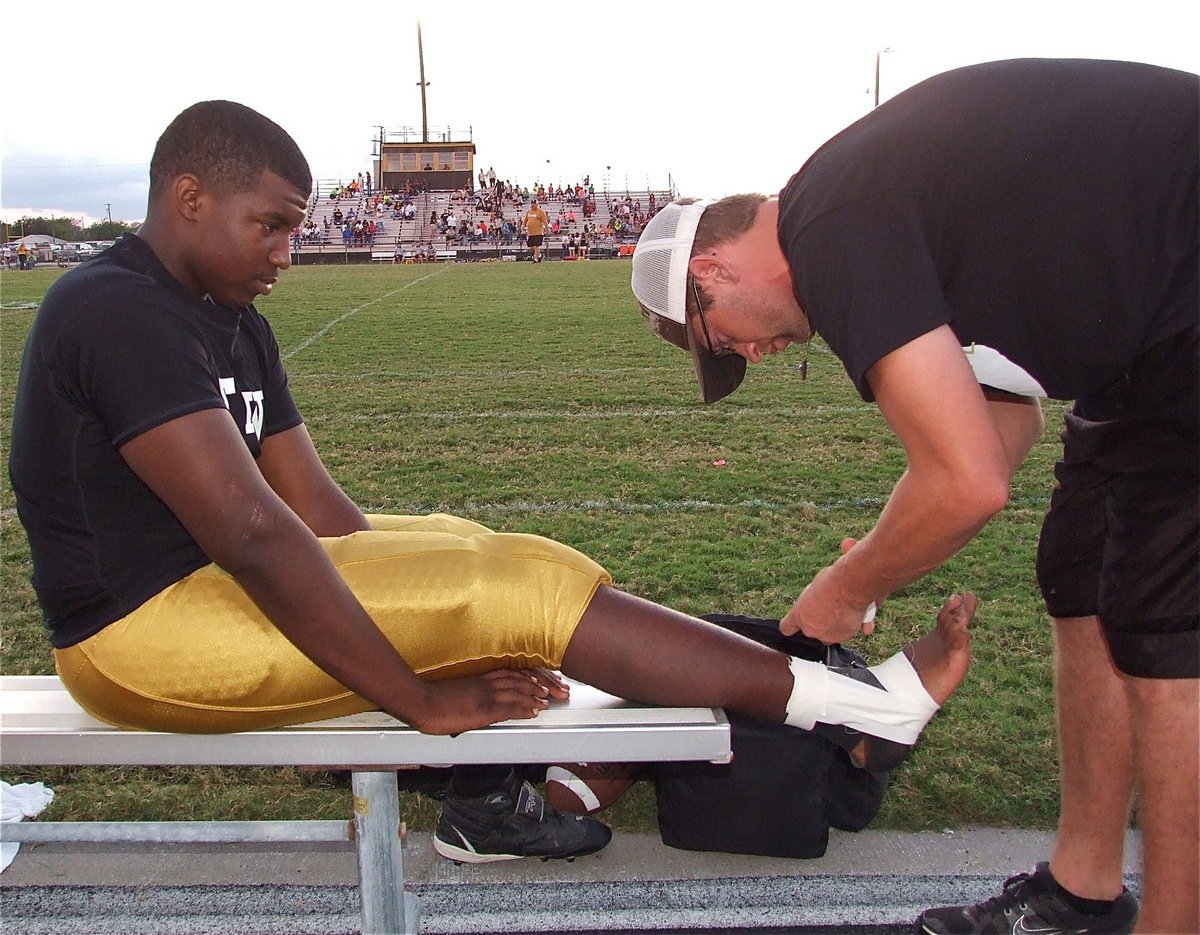 Image: JV Gladiator Justin Robbinson receives a tape job from Coach Nate Skelton.