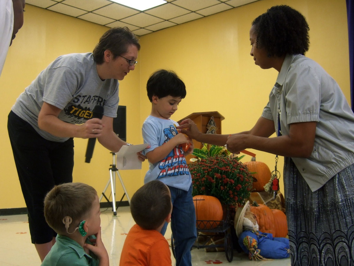 Image: Mrs. Wilson presenting this pre-K student with a perfect attendance award.