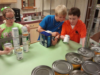 Image: 4-Hers Ethan Rogers and Hunter Hinz learned to sort the donated food items by expiration date before stocking the food pantry shelves.