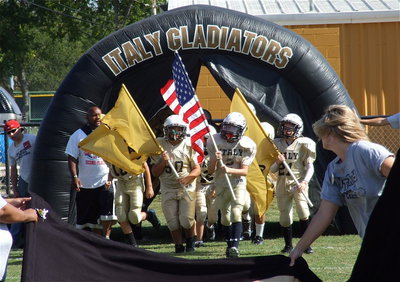 Image: Here come the A-Team Gladiators with Alex Garcia, Ethan Itson and Cade Brewer leading their squad out of the air tunnel and thru the banner.