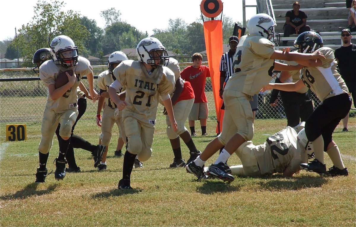 Image: Cade Brewer(21) leads Ethan Itson around the edge with Jonathan Salas(82) and Aedan Brewer(22) blocking.