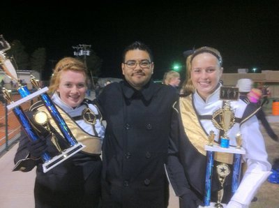 Image: Gladiator Regiment Marching Band director Jesus Perez proudly poses with (L) drum major Emily Stiles and® assistant drum major Madison Washington and their trophies.