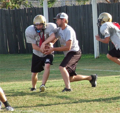 Image: Assistant coach Nate Skelton hands off to John Escamilla to simulate Cayuga’s offense.