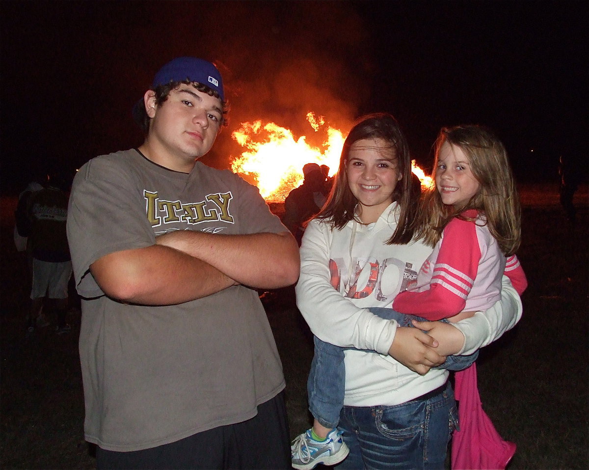 Image: Gladiator lineman Kevin Roldan, mascot Reagan Adams and IYAA cheerleader Mia Droll make the bonfire burn a little brighter.