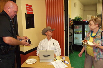 Image: Curtis Riddle charges Chief Diron Hill for a plate while talking with Jane Gorman Acker.