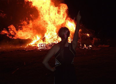 Image: IHS cheerleader Kelsey Nelson watches the bonfire burn while signaling that Italy is #1!