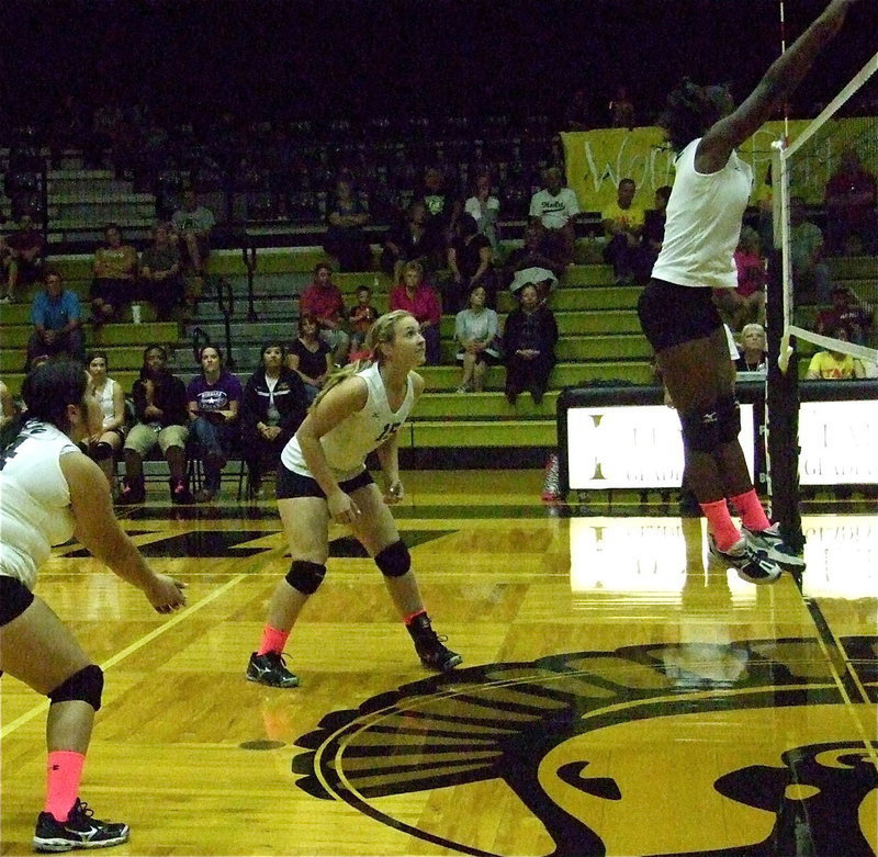 Image: Kortnei Johnson towers over the net for the block with Monserrat Figueroa(14) and Jaclynn Lewis(15) watching for a carom.