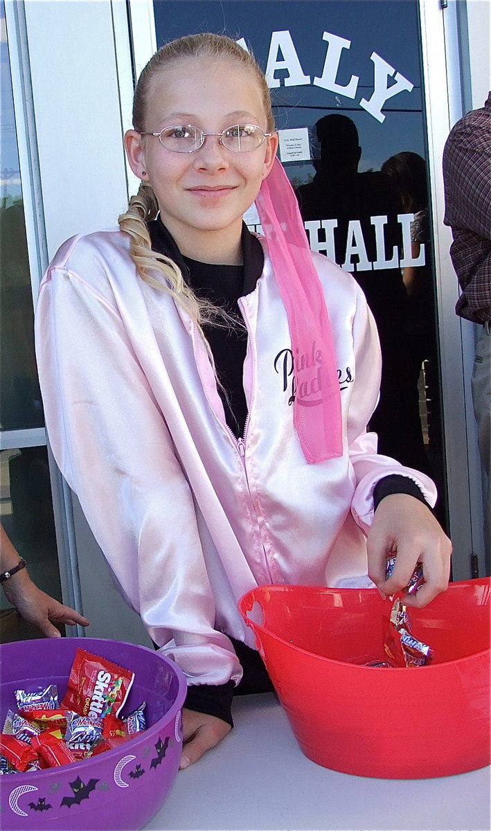 Image: Taylor Boyd, a member of the Pink Ladies, dishes out candy in front of city hall.