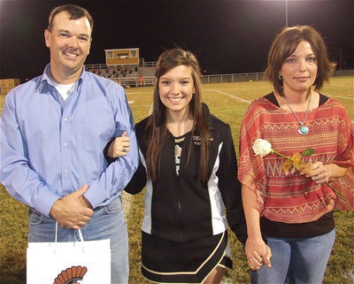 Image: Senior cheerleader Morgan Cockerham is escorted by her parents Paul Cockerham and Dustie Jones. Morgan will be attending Oklahoma Baptist University and become a nonprofit organization owner. Her most memorable moment in athletics was during 8th grade basketball when fellow senior, Alyssa Richards, tripped and fell while doing the run-out. lol