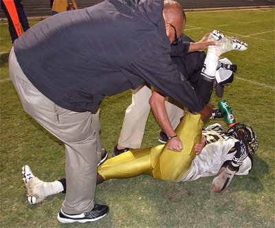 Image: Assistant coaches Larry Mayberry, Sr. and Nate Skelton stretch Ryheem Walker(10) during a pit stop.