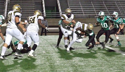 Image: Marvin Cox(3) lunges forward as Zain Byers(50), Darol Mayberry(58) and Kevin Roldan(60) create running lanes.