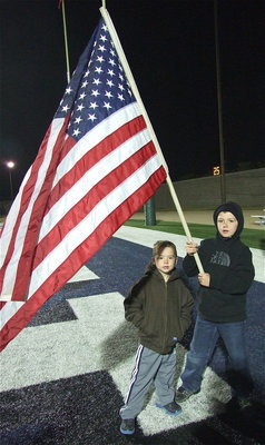 Image: Bryce DeBorde and little brother Garred Wood keep the flag waving before handing it over to the players.