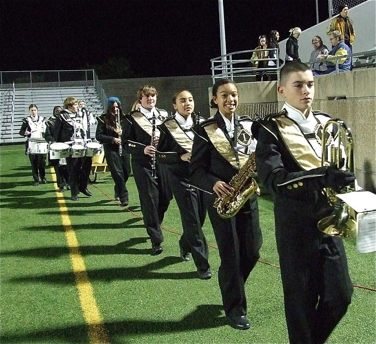 Image: Elijah Garcia, April Lusk, Vanessa Cantu and Trevor Patterson help lead the band onto the field for their halftime performance.