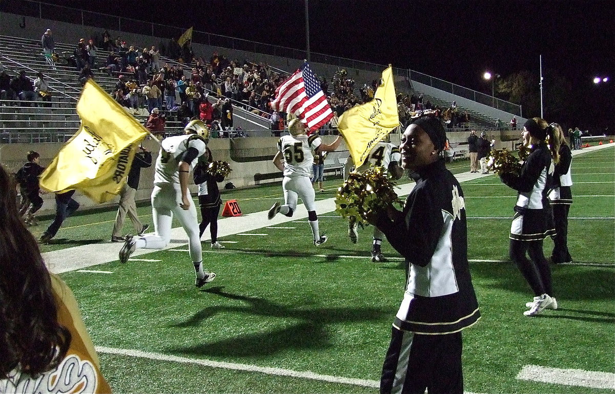 Image: Senior Gladiators Cole Hopkins(9), Zackery Boykin(55) and Adrian Reed(64) lead team Italy onto the field of battle against Valley View for the area championship as IHS cheerleader K’Breona Davis and squad mates welcome their guys.