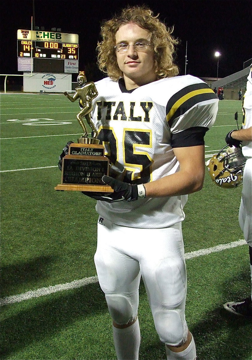 Image: Shad Newman(25) displays the Area Championship trophy as the final score glows in the background.