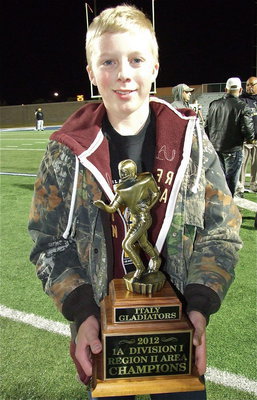 Image: D.J. Hollywood, son of Gladiator head coach Hank Hollywood, displays the team’s area championship trophy proudly.