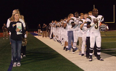 Image: Up front, Marvin Cox(3) represents the Gladiators and coaches during the National Anthem while Bailey Eubank represents Italy’s statisticians, cheerleaders and team managers as Italy prepares to take on the Honey Grove Warriors for the regional semifinal championship at Ken Autry Davis Field in Wills Point.