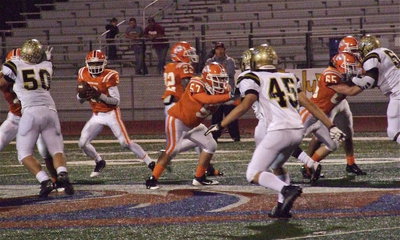 Image: Zain Byers(50), Hunter Merimon(45) and Adrian Reed(64) try keeping Warrior quarterback Jeremy Patt(3) in check.