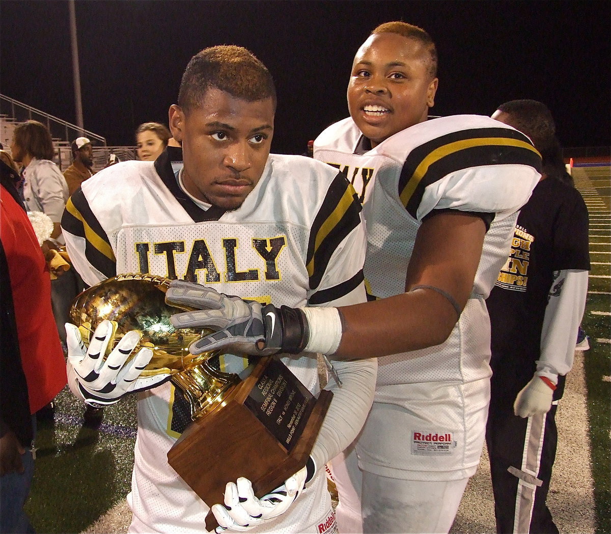 Image: Jalarnce Jamal Lewis(21) and Darol Mayberry(58) covet the trophy while posing for pictures after upsetting Honey Grove 33-20 for the regional semifinal championship.