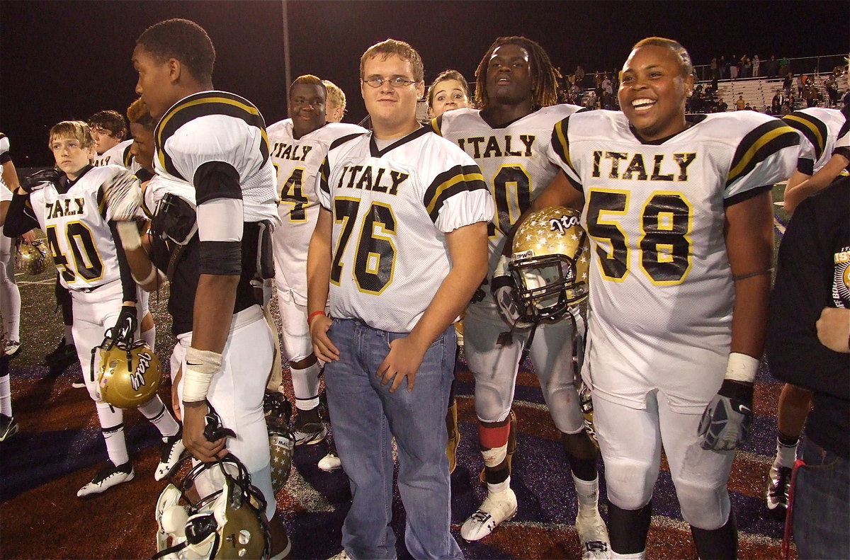 Image: Clayton Miller(40), Eric Carson(12), Adrian Reed(64), Colin Newman(76), Gladiator mascot Reagan Adams, Ryheem Walker(10) and Darol Mayberry(58) show respect during the playing of Honey Grove’s school song.