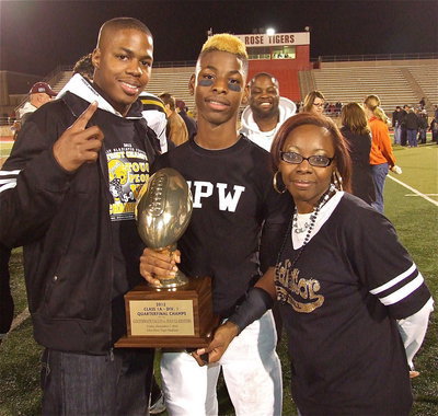 Image: Gladiator junior Eric Carson(12) displays Italy’s quarterfinal championship trophy with family members Detrick Green and mom Timeka Green.
