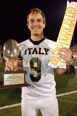 Image: Senior receiver Cole Hopkins(9) displays Italy’s quarterfinal championship trophy after defeating the Goldthwaite Eagles 14-3 in Glen Rose. Hopkins caught 2 passes for 45 yards to help setup both Gladiator touchdowns and scored 2-points on a conversion catch. The Gladiator senior also punted twice averaging 40 yards each with a long of 46-yards to the enemy’s 15-yard line.