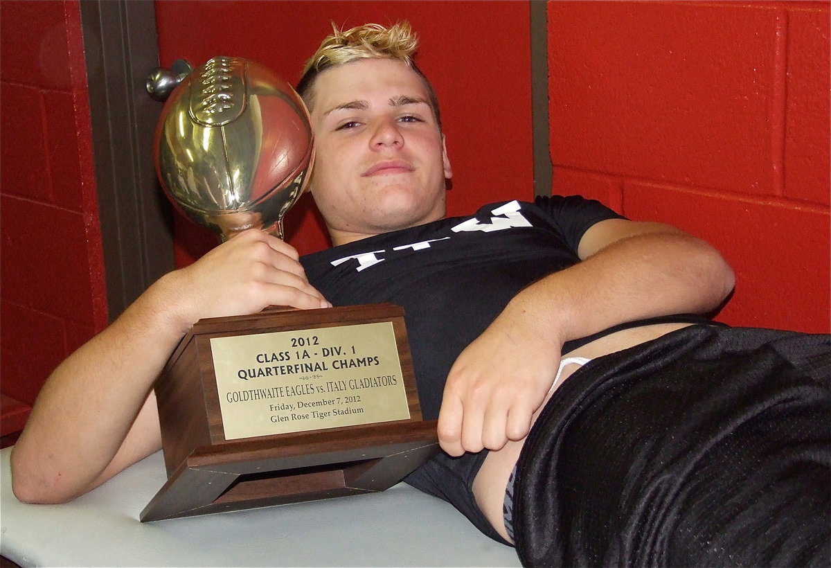 Image: An injured Hunter Merimon(45) is handed the quarterfinal championship trophy inside the locker room by his teammates after the game. Merimon had 3 tackles including 1 solo tackle against Goldthwaite while helping to contain the Eagle offense.