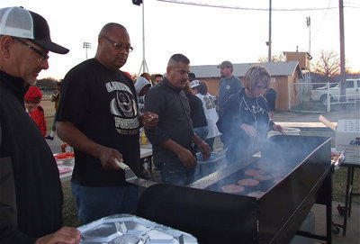 Image: Vincent Jacinto, Larry Mayberry, Sr., Mark Jacinto and Lisa Jacinto help prepare hamburgers for the Gladiator band, football players, coaches, cheerleaders and managers.