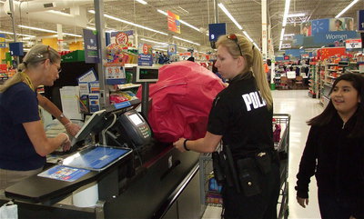 Image: Officer Shelbi Landon and Arley Salazar get help checking out from Wal-Mart clerk Rebecca Mentzel.