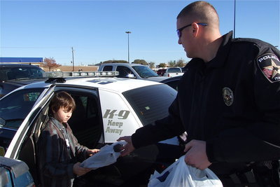 Image: Mitchell Darrell gets help loading the patrol car from Officer Mike Richardson.
