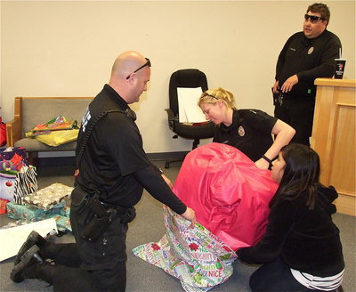 Image: Officer’s need assistance! Arley Salazar tries to help Officer Shawn Martin and Shelbi Landon fit a very large bean bag into a very small wrapper as Officer Eric Tolliver pretends not to notice. All part of the Italy Police Department’s “Shop with a Cop” experience, which is fun thrill for the students.