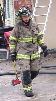 Image: Reece Marshall with the Forreston Volunteer Fire Department emerges from the scorched home with axe in hand.