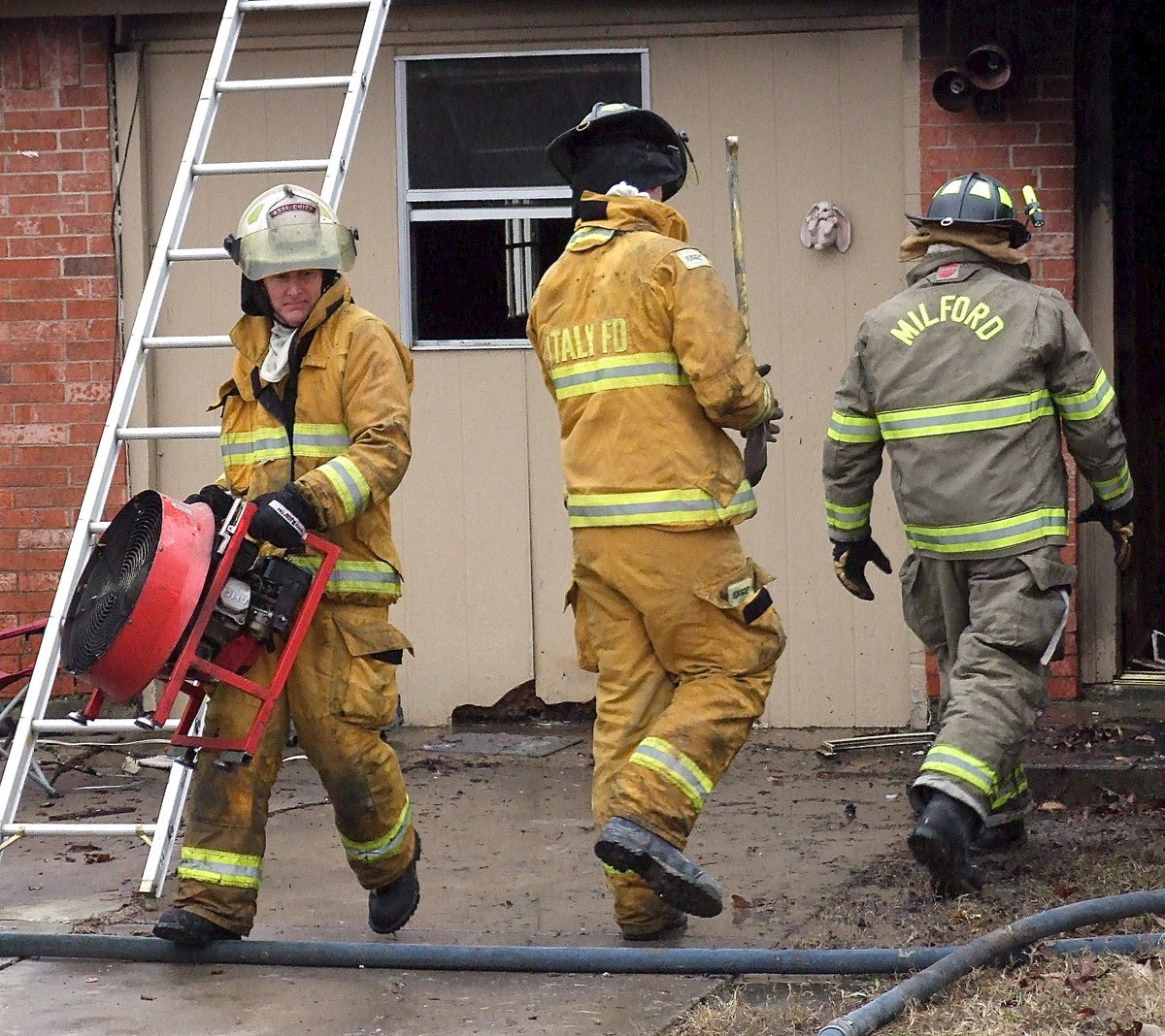 Image: Italy Firefighter Randy Boyd removes a fan which had been setup inside of the structure to clear the home of smoke so the firefighters could see better and breathe easier.