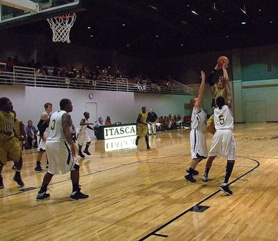 Image: Gladiator center Cole Hopkins(21) uses his 6’8" height advantage to get a shot off over two Itasca defenders.