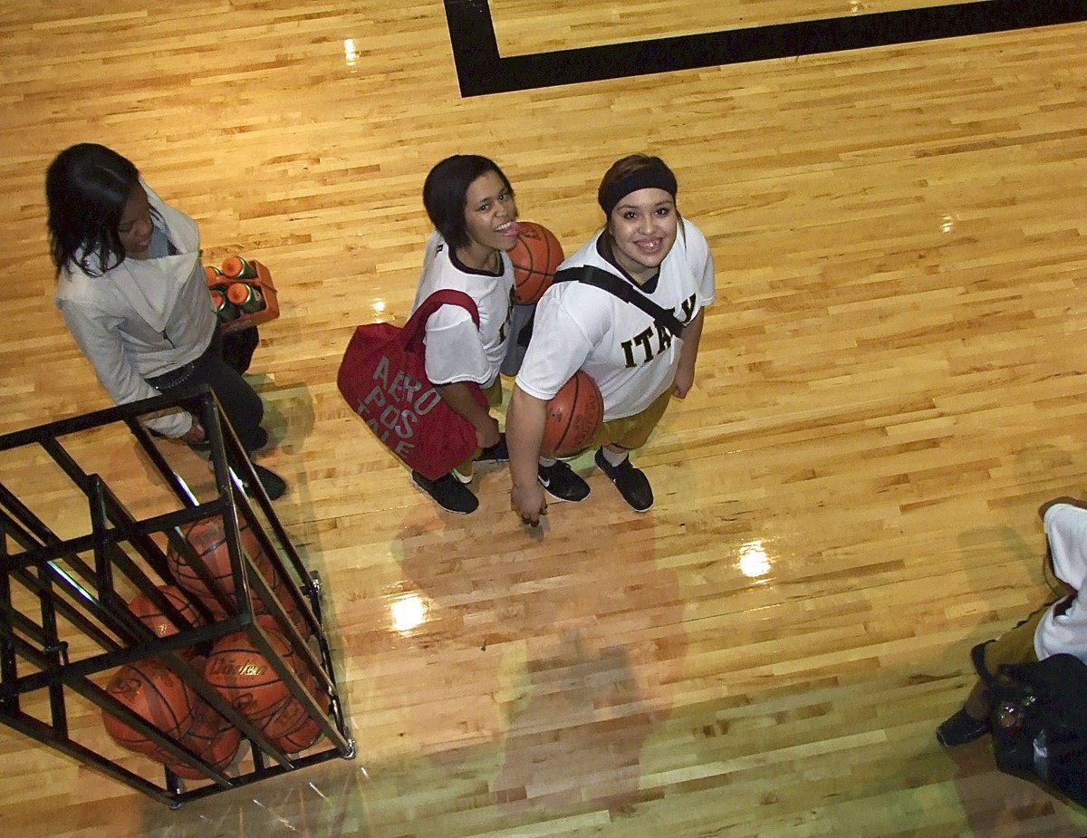 Image: Manager Charisma Anderson follows Alex Minton and Monserrat Figueroa onto the court for a district duel between Italy and Itasca.